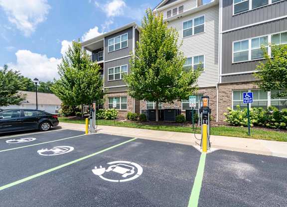 A parking lot with a black car and a charging station.