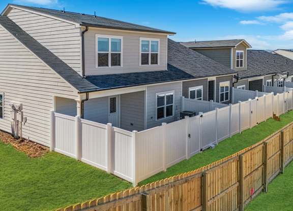 A house with a grey roof and a white fence.