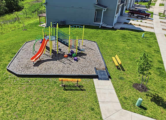 A playground with a slide, swings, and a bench.