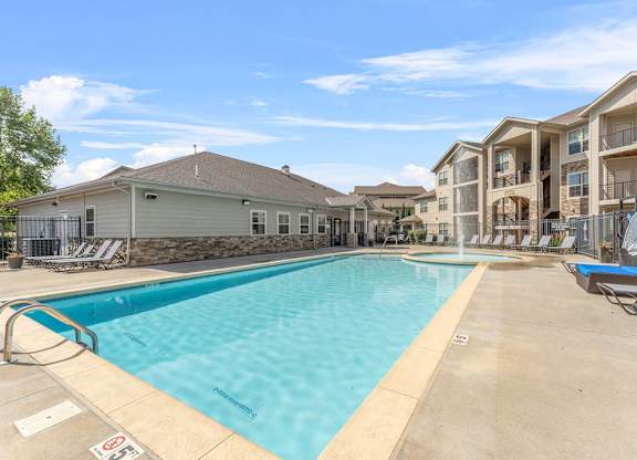 A swimming pool in a residential area with apartment buildings in the background.