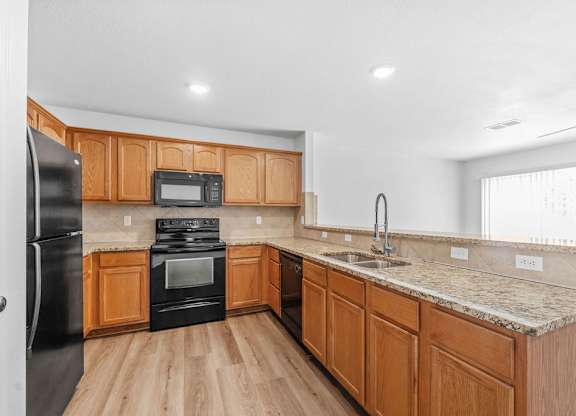 A kitchen with wooden cabinets and black appliances.