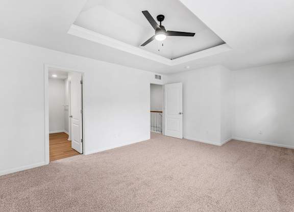 A room with a ceiling fan and carpeted floor.