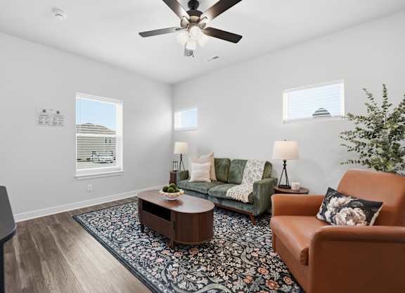 A living room with a brown couch, a coffee table, and a ceiling fan.