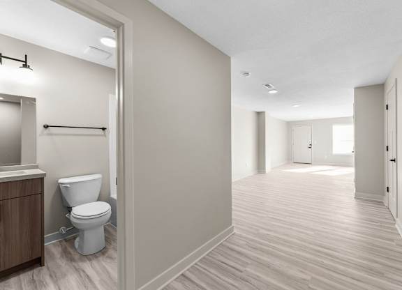 A bathroom with a toilet and a wooden floor.