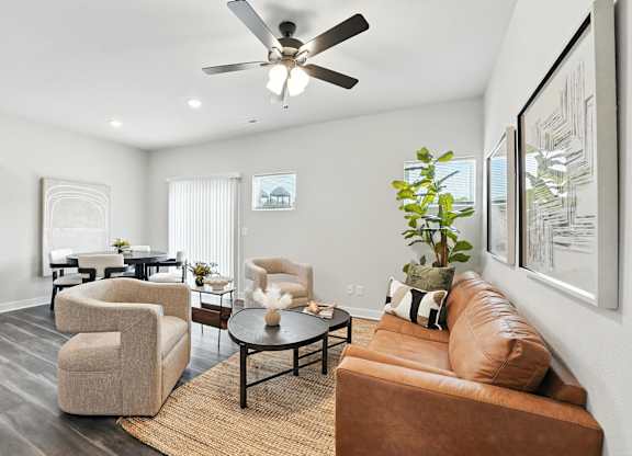 A living room with a brown couch, a coffee table, and a ceiling fan.