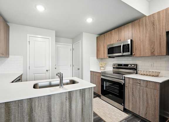A modern kitchen with a sink, oven, and microwave.