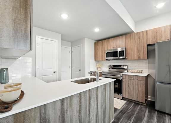 A modern kitchen with a white countertop and stainless steel appliances.