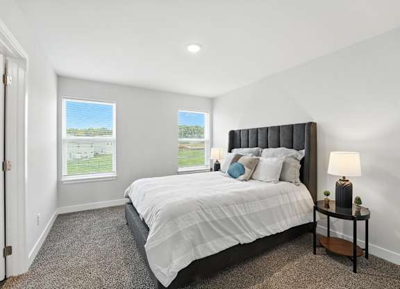 A bedroom with a large bed and a window overlooking a green field.