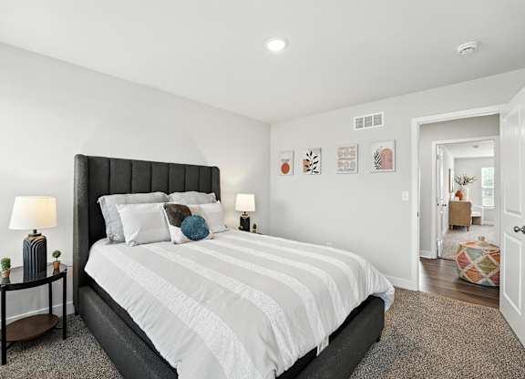 A bedroom with a large bed and a nightstand with a lamp.