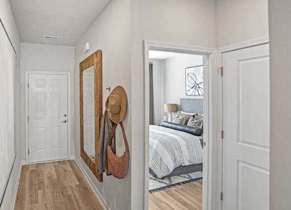 A hallway with a mirror and a hat hanging on it.
