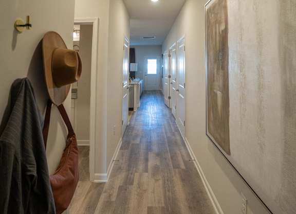 A long hallway with a coat and hat hanging on the wall.
