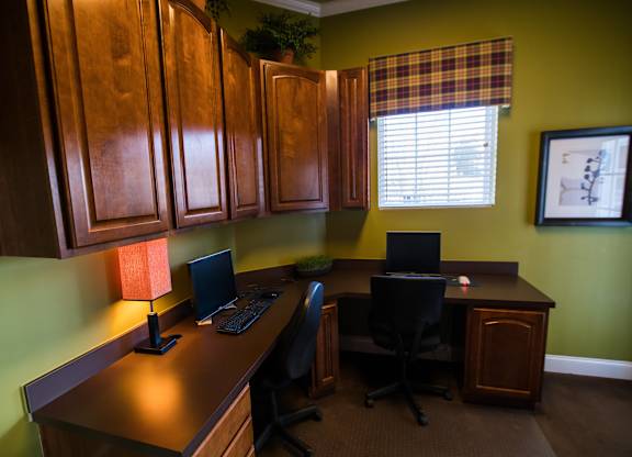 A home office with a green wall and a window with blinds.