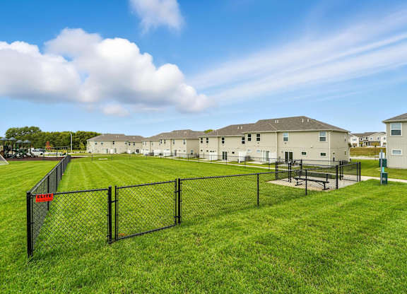 A grassy field with a fence and a building in the background.