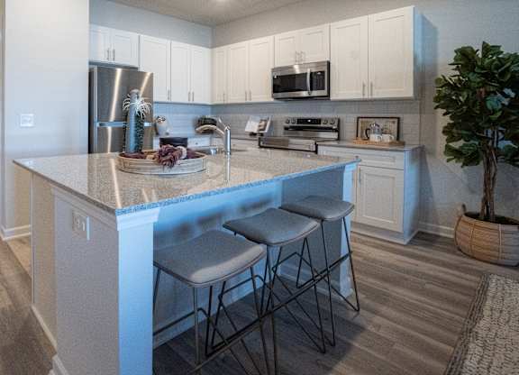 A kitchen with a white island and bar stools.