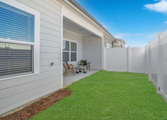 A backyard with a white fence and a small table and chairs.