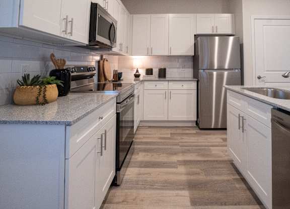 A kitchen with white cabinets and a stainless steel refrigerator.