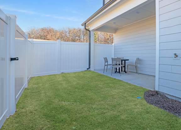 A backyard with a white fence and a small table and chairs.