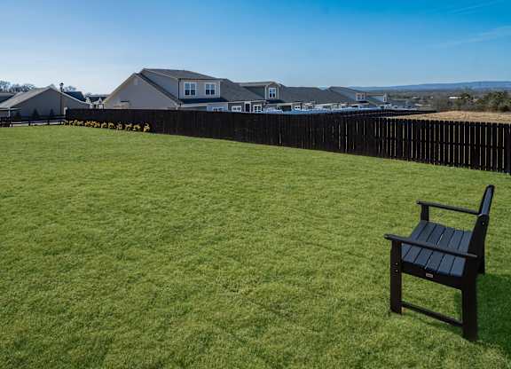 A black chair is on a grassy lawn with a house in the background.