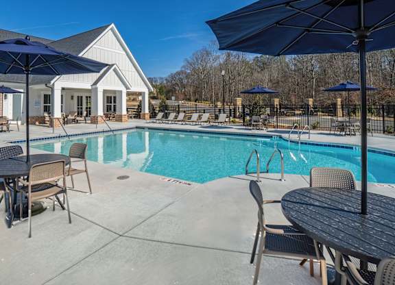 A pool area with a table and chairs and umbrellas.