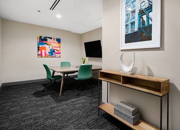 A conference room with a table, chairs, and a painting on the wall.