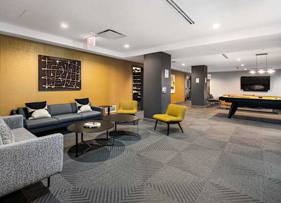 A room with a grey carpet and a grey sofa.