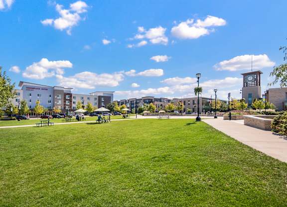 A park with a grassy area and a clock tower in the background.