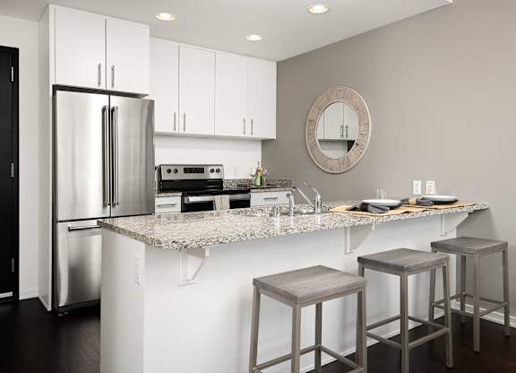 a kitchen with white cabinets and a counter top with three stools
