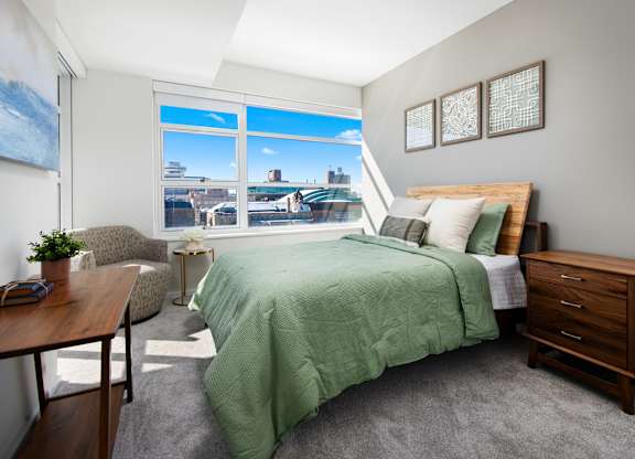 a bedroom with a large window and a green bed