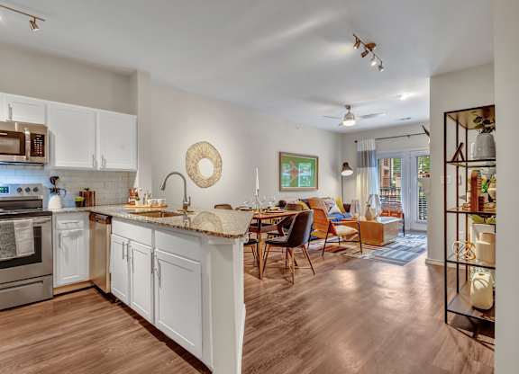 A modern kitchen with white cabinets and a wooden floor.