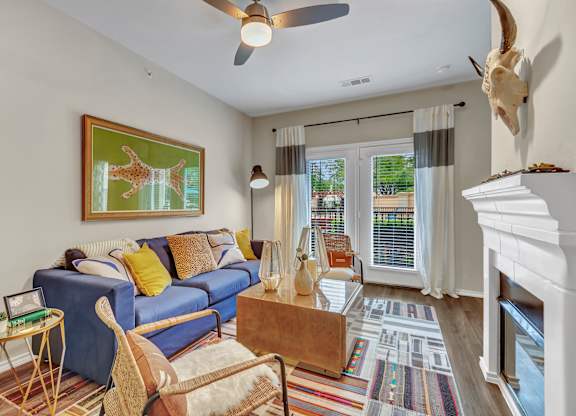 A living room with a blue couch and a painting of a giraffe on the wall.