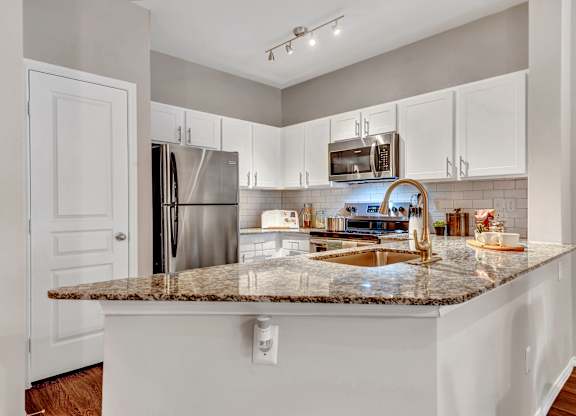 A kitchen with a granite countertop and stainless steel appliances.