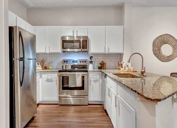 A modern kitchen with a stainless steel refrigerator, microwave, oven, and sink.