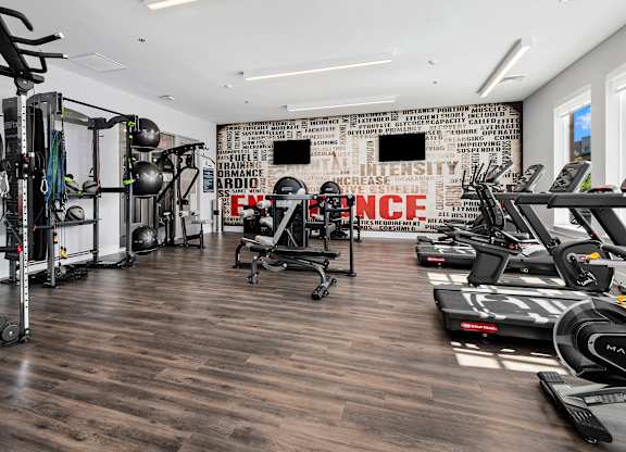 A gym with a variety of equipment including treadmills, weights, and exercise machines.