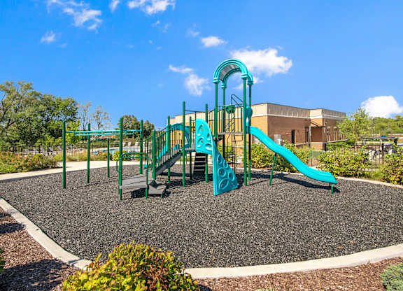 A playground with a green slide and a climbing frame.