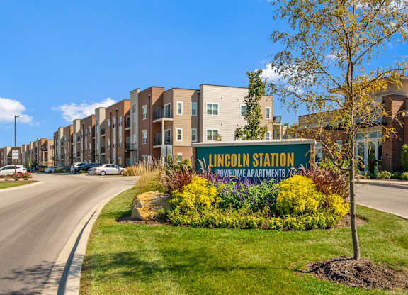 A street view of Lincoln Station townhomes with a sign in front.