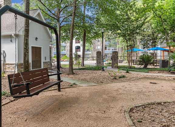 A swing set in a playground with a white building in the background.