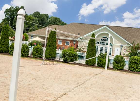 A white pillar stands in front of a house with a brown roof.
