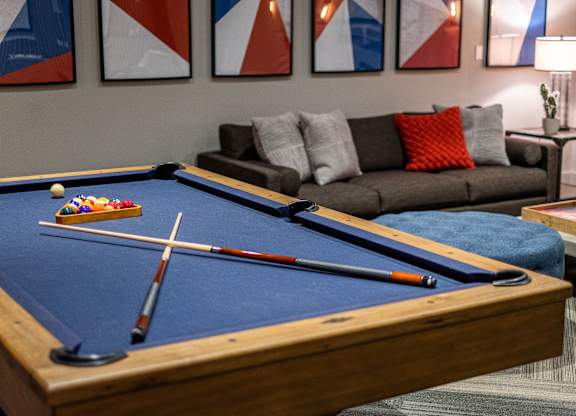 A pool table with a couch and a lamp in the background.