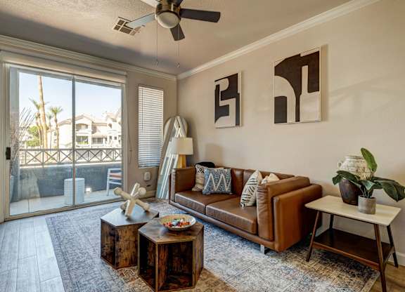 A living room with a brown couch, a coffee table, and a ceiling fan.