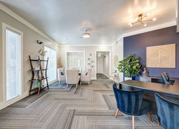 A modern office space with a grey carpet and blue chairs.