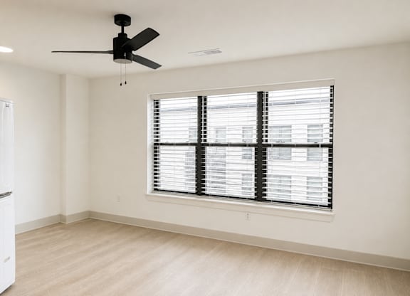 A room with a ceiling fan and a window with blinds.