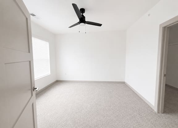 A room with a ceiling fan and carpeted floor.