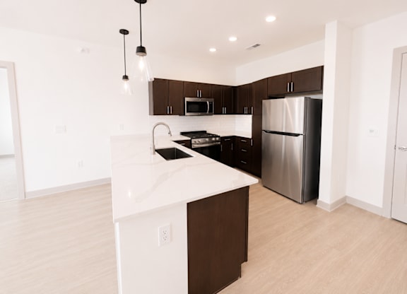 A kitchen with a white counter top and a stainless steel refrigerator.