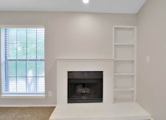 A white fireplace with a shelf above it in a room with a window.
