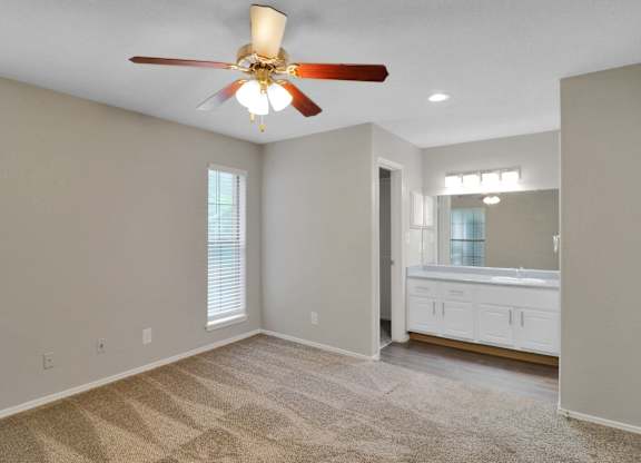 A room with a ceiling fan and carpeted floor.