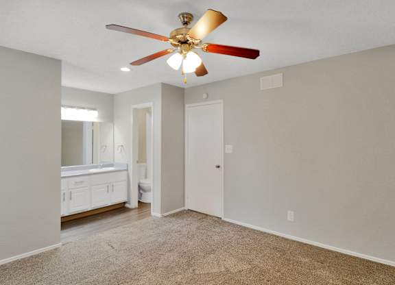 A room with a ceiling fan and carpeted floor.