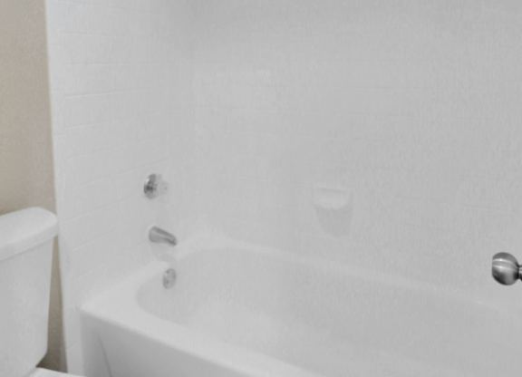 A white toilet sits next to a white bathtub.