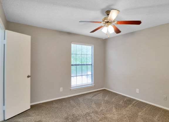 A room with a ceiling fan and a window.