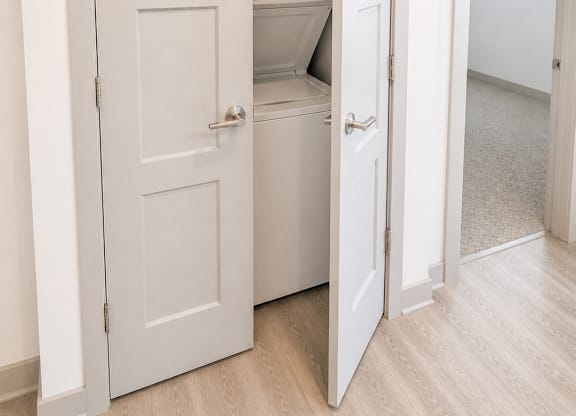 A white door is open to reveal a small kitchen.
