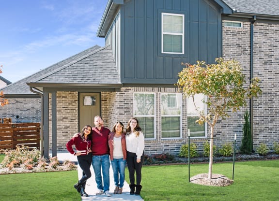 a family poses in front of a house